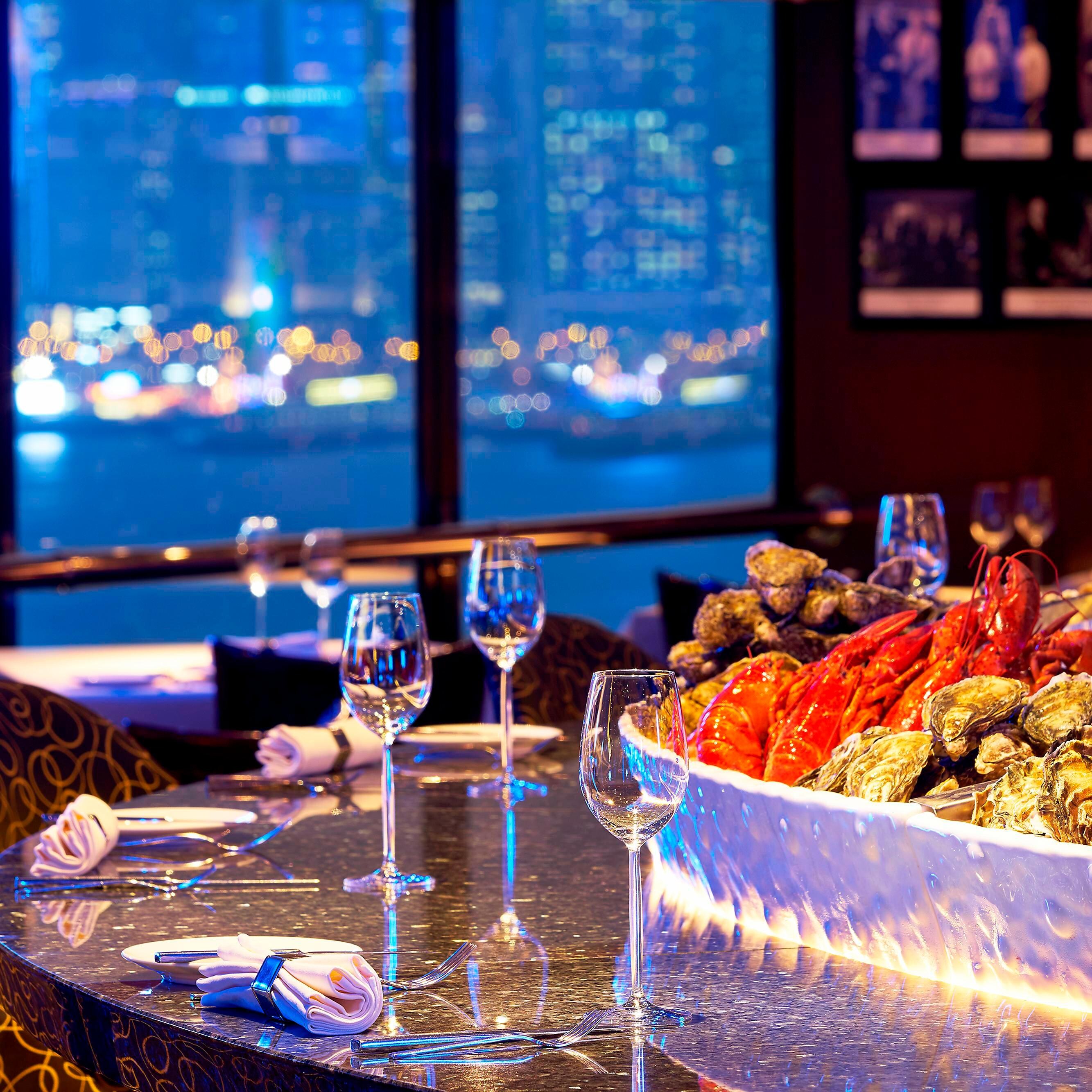 摆放着生蚝和两杯饮品，背景是海景