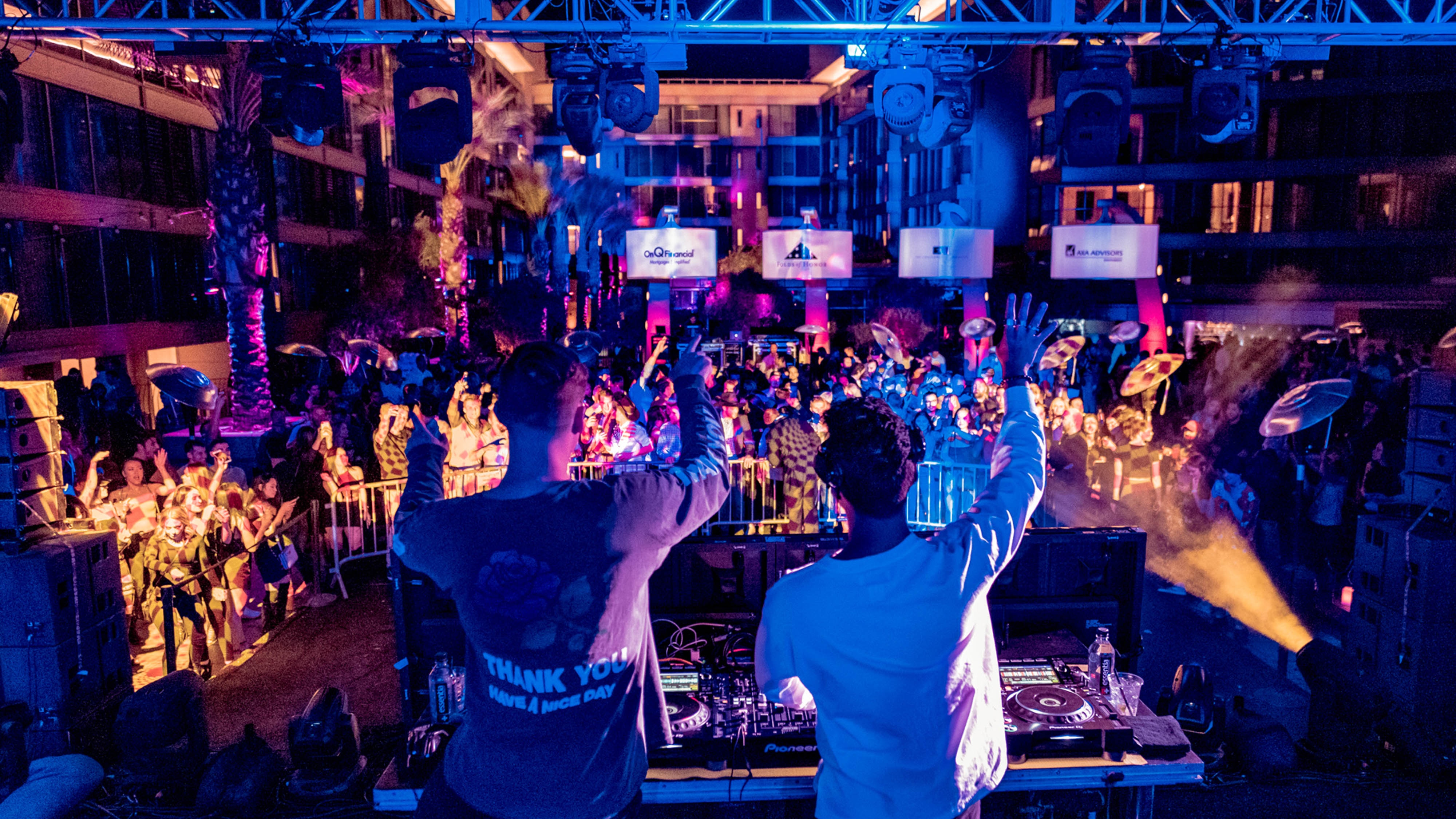 充满活力的俱乐部场景，人群在蓝色灯光下听着音乐舞动，舞台中央有一个巨大的发光字母“w”​