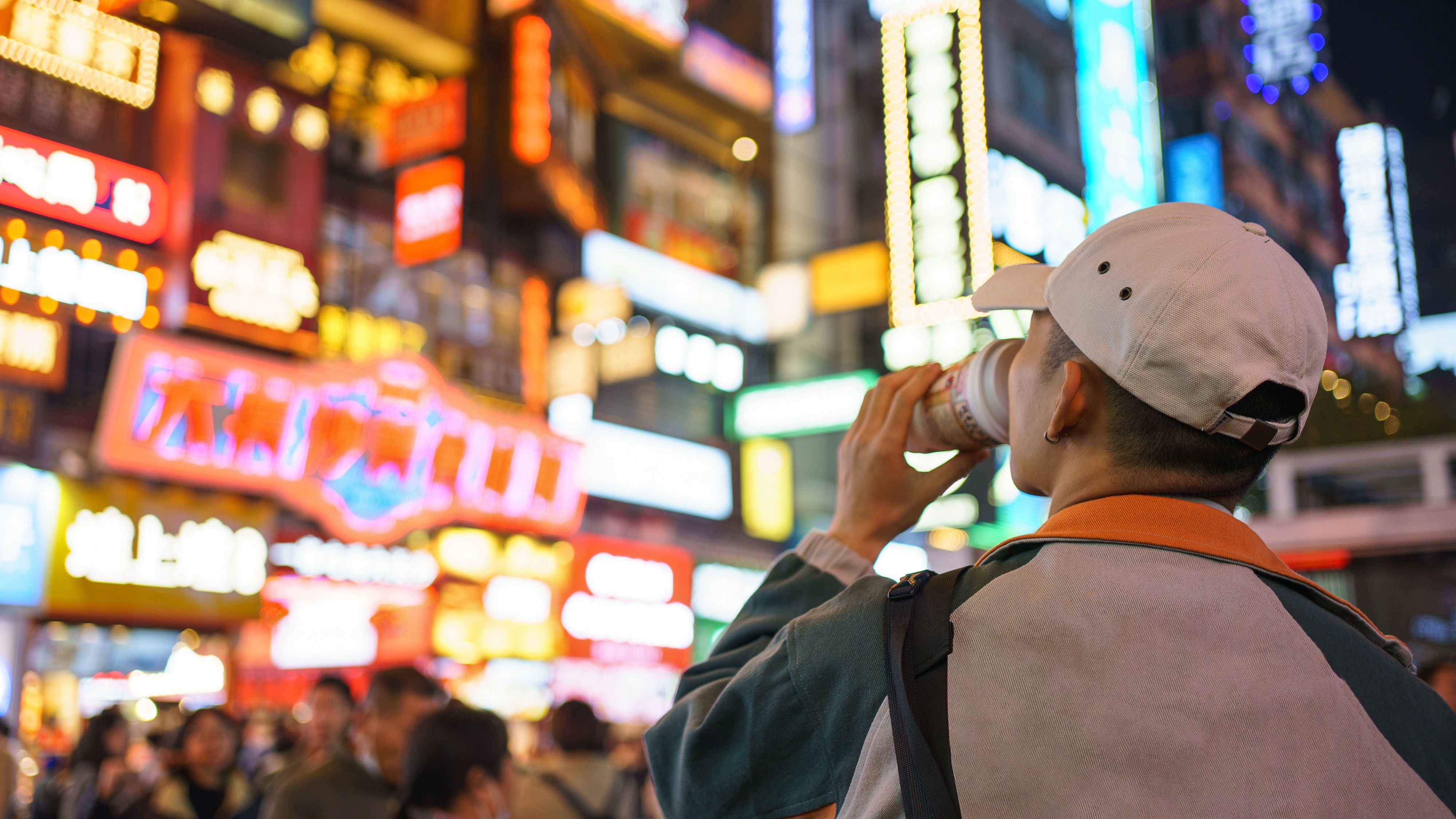 男生观看长沙夜晚街边五颜六色的灯牌