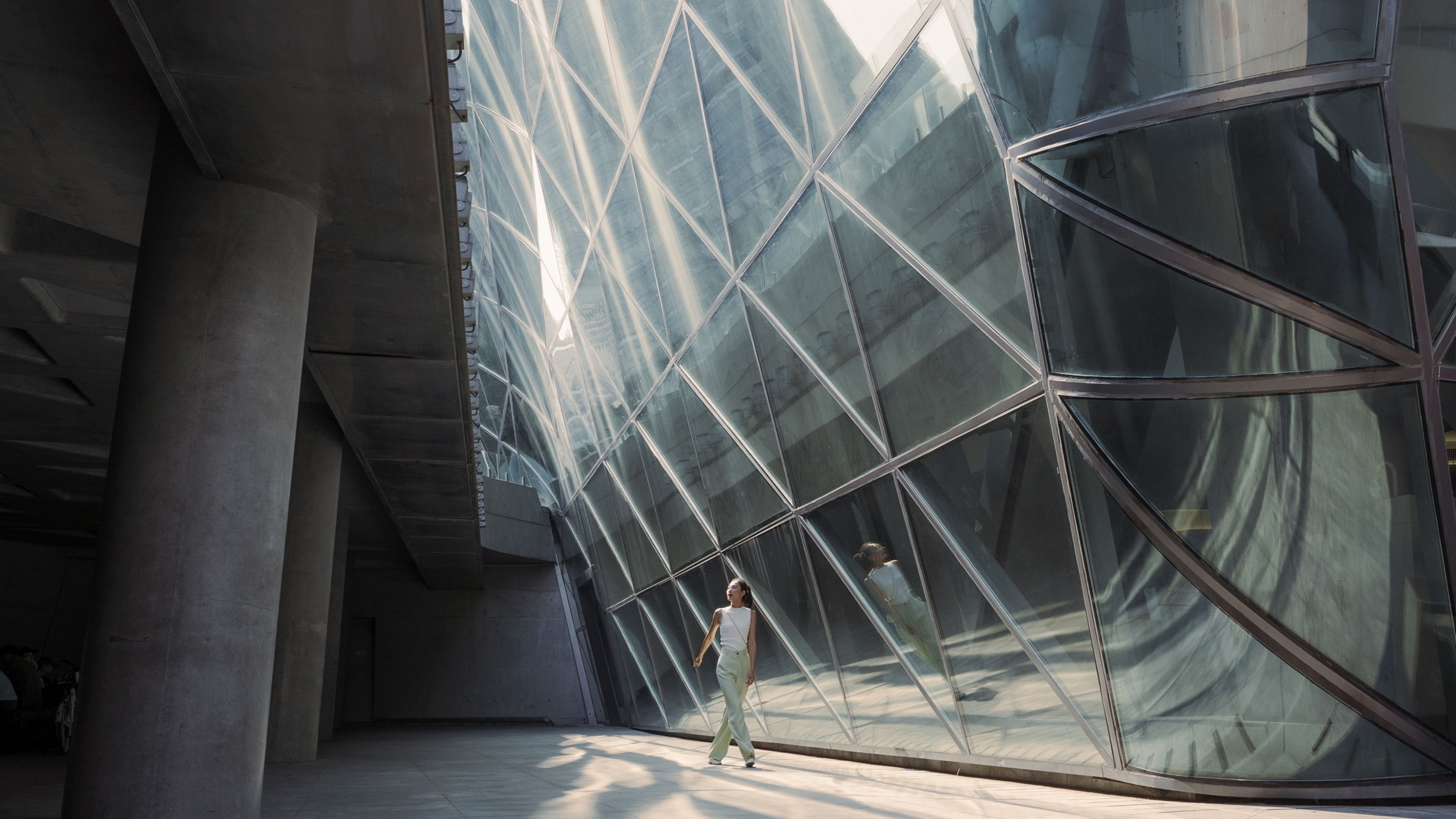 女生望着自己在现代的建筑物镜子中的映像