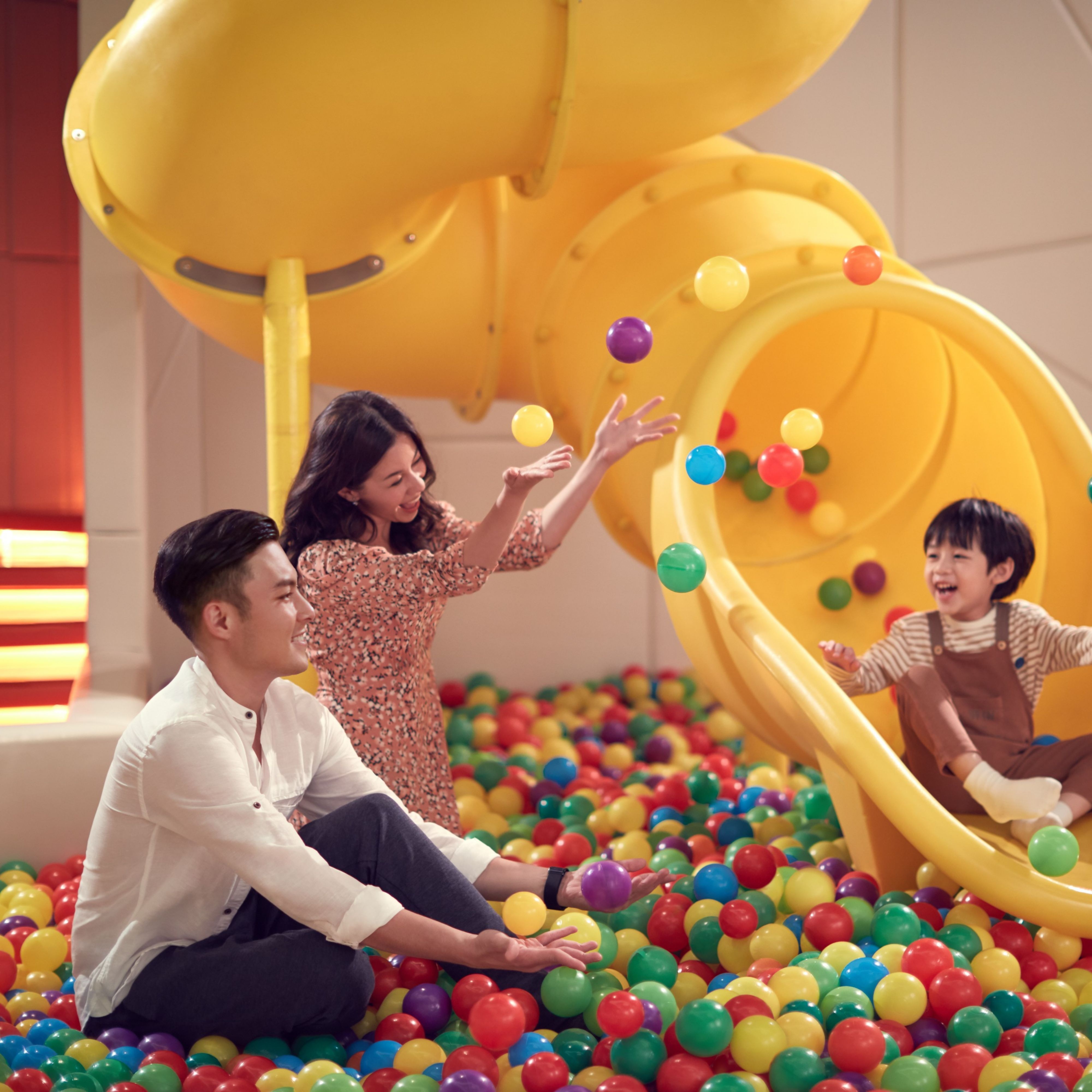 弹力球池中，孩子在家长陪伴下畅玩滑梯
