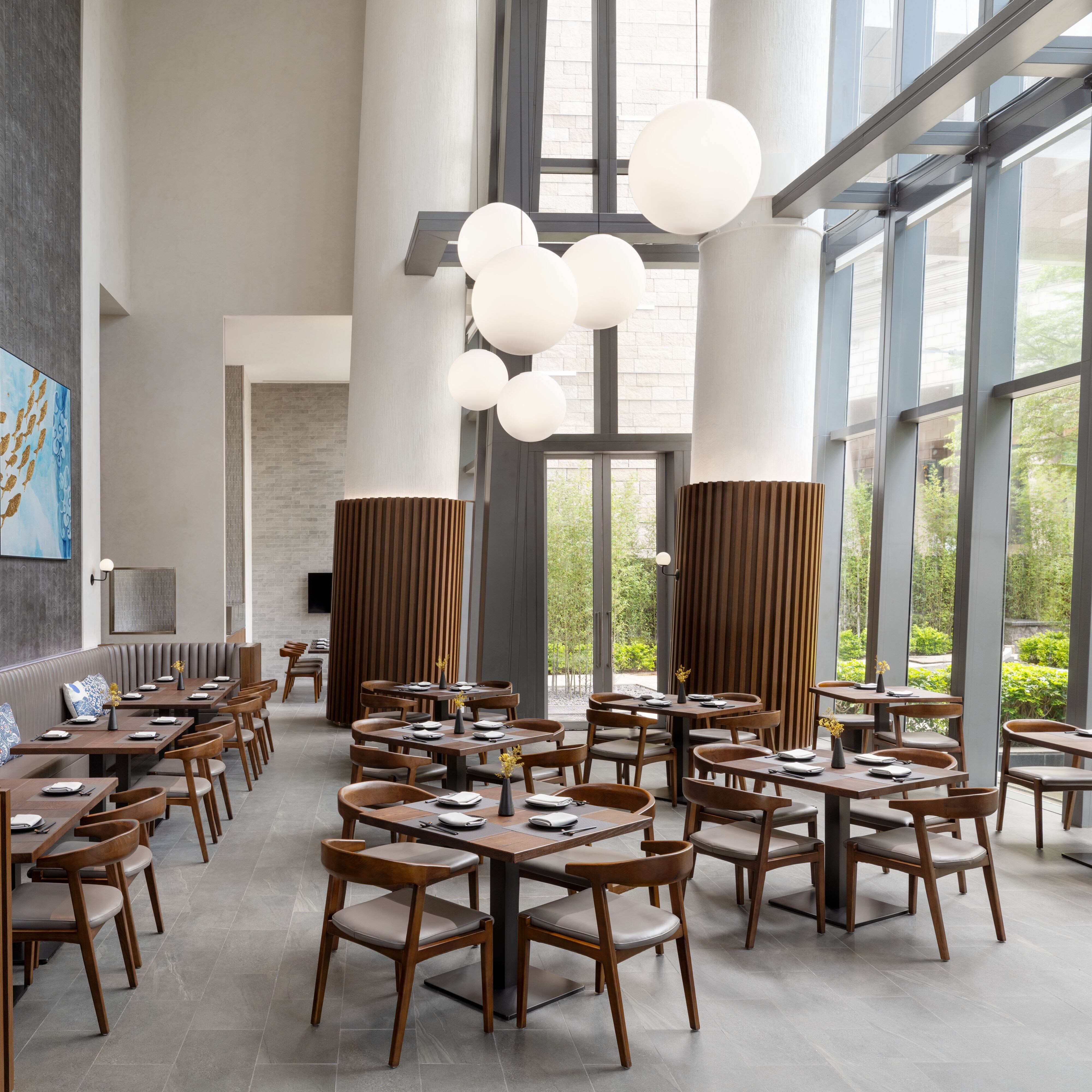 木制桌子、灰色墙上的艺术品、气泡灯和大窗户