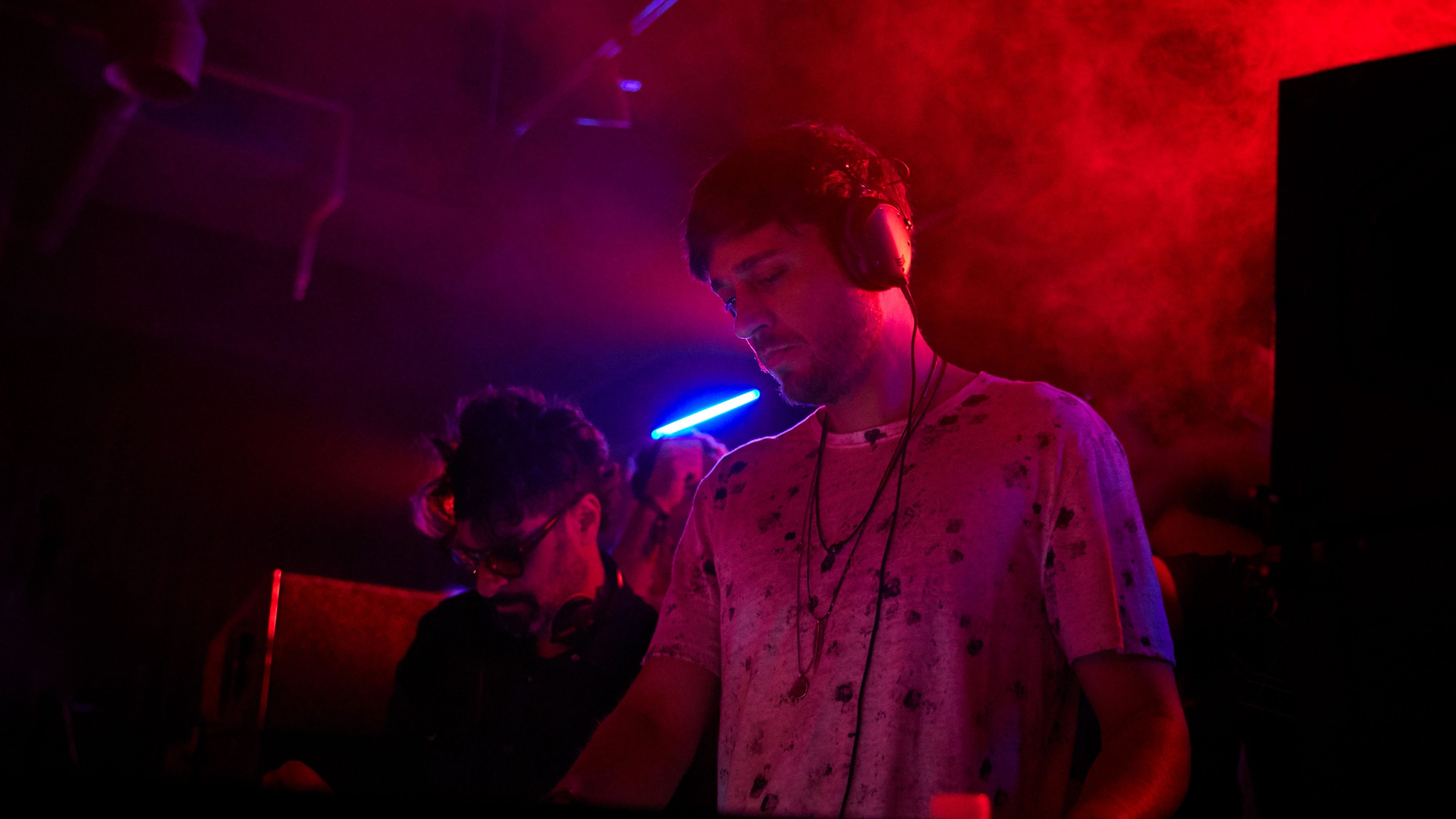 一位穿着前卫的年轻女性DJ在W舞台上混音，背后是W型的背景灯光​