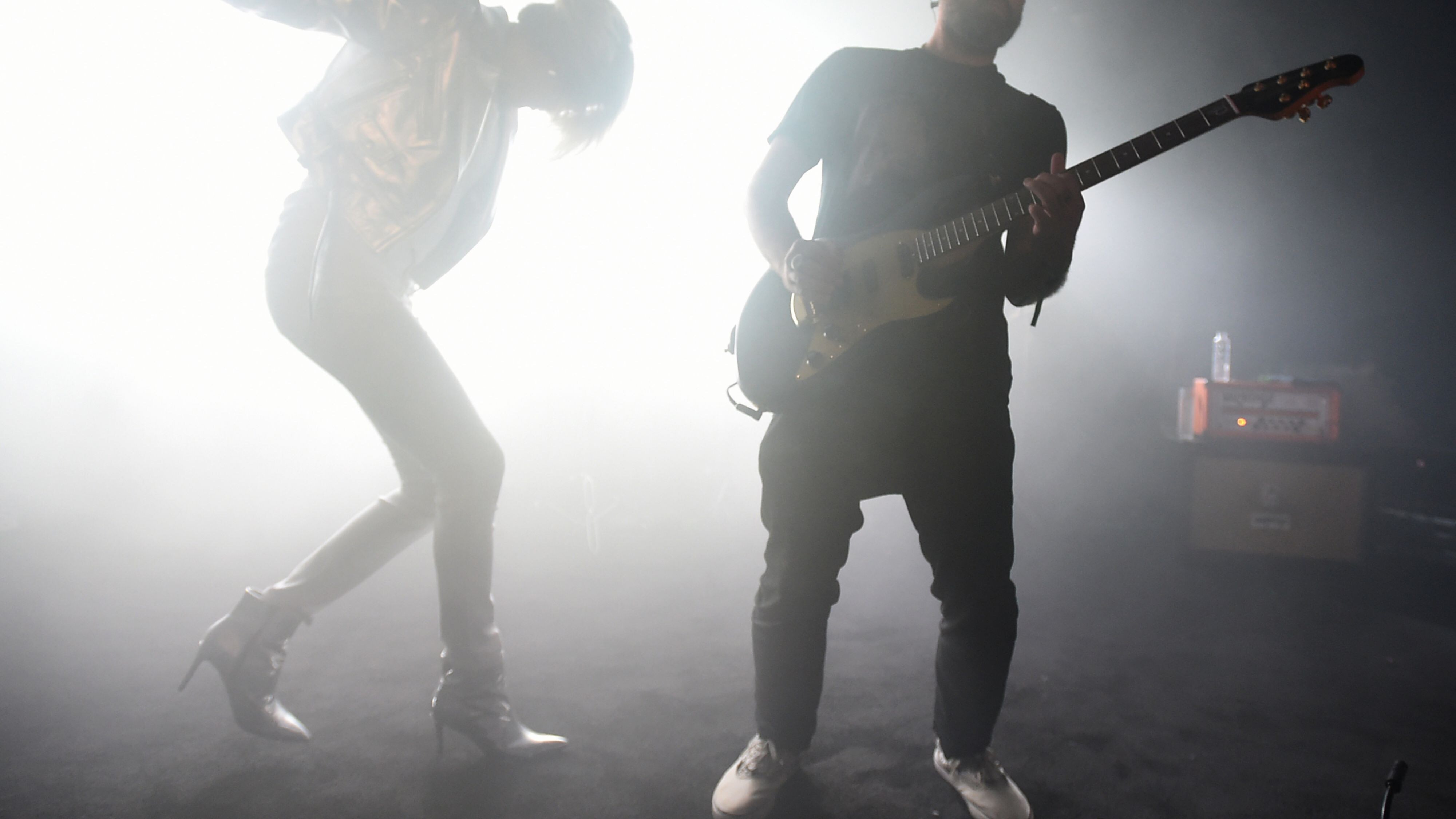 一位金发 DJ在俱乐部里表演，她戴着耳机、穿着亮片服装，俱乐部里是蓝色霓虹灯，不少观众在用手机录影。​