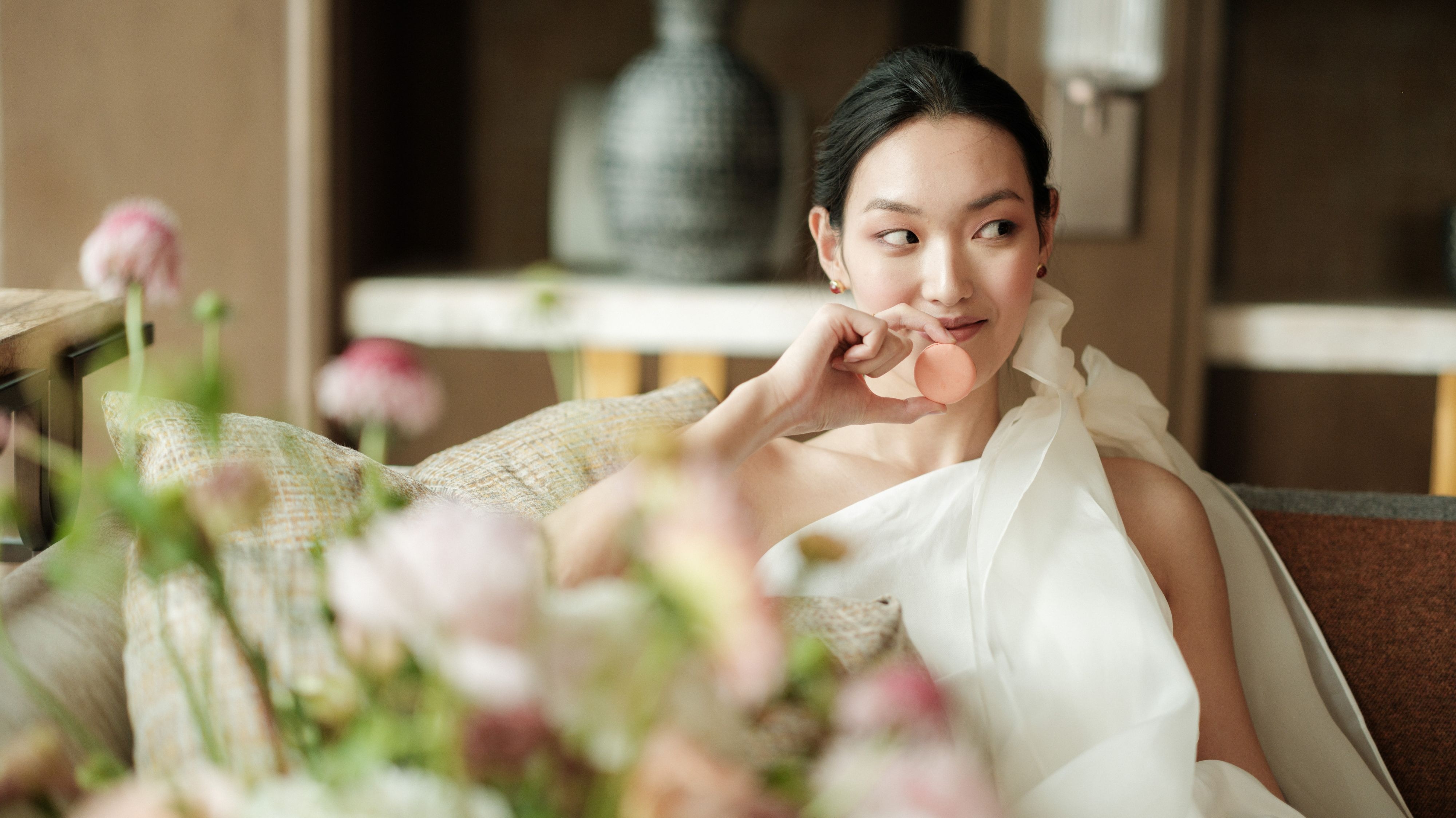 一位女士在花艺环绕的沙发上悠闲地休息，面带微笑。