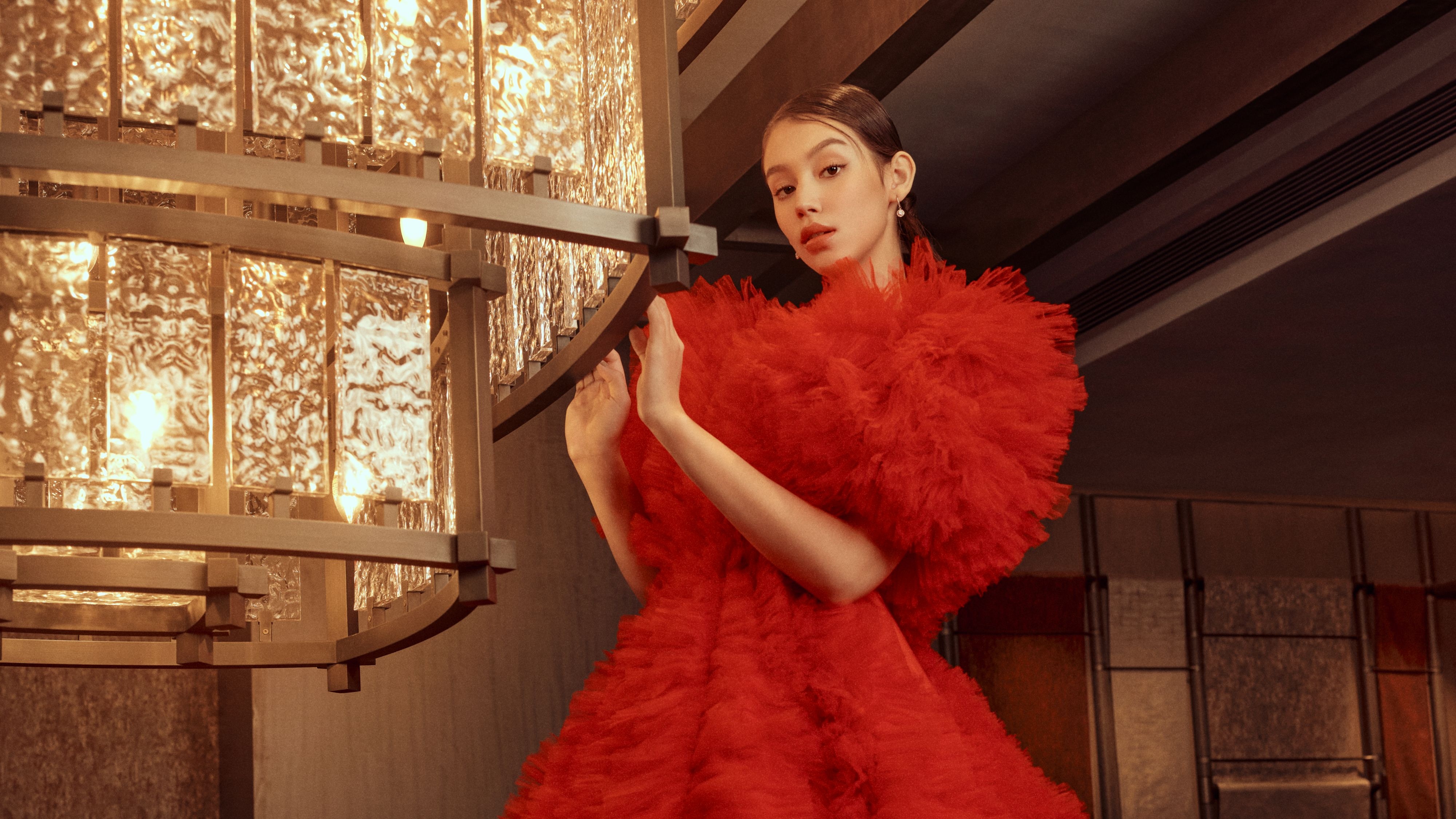 一个身穿红色礼服的新娘站在瑞吉酒店的阶梯上